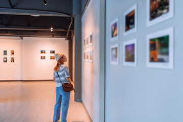 Woman visiting art gallery her looking pictures on wall watching photo frame painting at artwork museum people lifestyle concept.