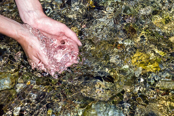 female hands scoop up fresh water in a fast river