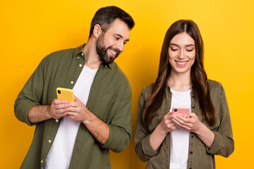 Sticker - Photo of positive couple spend free time in smartphones surfing in social media isolated on yellow color background