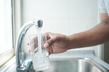 refilling glass of water from a faucet tap 