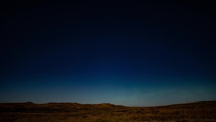 Wall Mural - dark blue night sky with moving stars and aurora flashing on the horizon. set the prairies in autumn