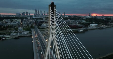 Canvas Print - Aerial panorama of Warsaw city skyline with illuminated famous bridge on Vistula River at sunset. Warm sun on the horizon