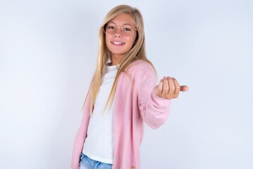 caucasian blonde little girl wearing pink jacket and glasses over white background , inviting you to come, confident and smiling making a gesture with hand, being positive and friendly.