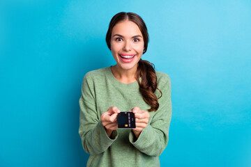 Poster - Portrait of cheerful positive girl hands hold give you debit plastic card isolated on blue color background