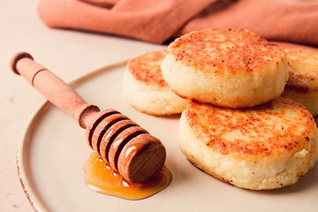 Wall Mural - Cottage cheese pancakes, with honey, close-up, on a beige table, selective focus, no people,