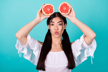 Wall Mural - Photo of cute funny lady wear white top holding two orange halves head sending you kiss isolated turquoise color background