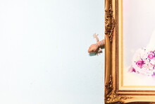 A Large Gecko Clings To A Cement Wall And Lives Behind A Picture Frame.