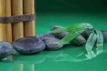 Green Leaf On Rocks With Bamboo Sticks On The Water Against Green Blurred Background
