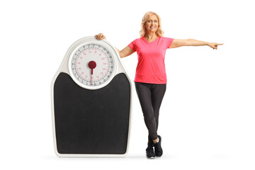 Sticker - Full length portrait of a mature woman in sportswear posing with a big measuring and pointing to the side