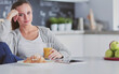 © lenets_tan - Young woman with orange juice and tablet in kitchen.