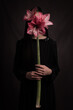 © Milou Dirks - studio art portrait of woman in black dress holding pink amaryllis flower hiding her face