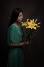 Classic Studio Fine Art Portrait Of Asian Woman In Green Dress Holding Yellow Flowers