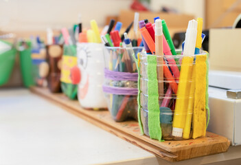 many coloring pens and pencils in pencil holders on worktable in art class, studio or school. arts a