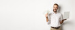 © Mix and Match Studio - Business and e-commerce. Excited businessman holding money dollars and laptop, working online, standing over white background