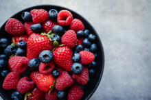 Overhead Of Bowl Of Fresh Mixed Berries On Grey Background.