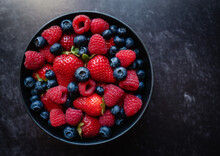 Top View Of Bowl Of Fresh Mixed Berries On Black Background.