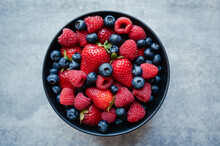 Top View Of Bowl Of Fresh Mixed Berries On Grey Background.