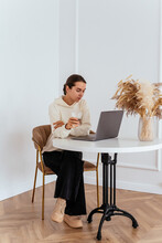 A Young Girl Is Working At A Laptop In A Bright Apartment At A T
