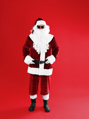 Full length portrait of Santa Claus with sunglasses on red background