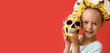 Little girl with painted human skull on red background. Celebration of Mexico's Day of the Dead (El Dia de Muertos)