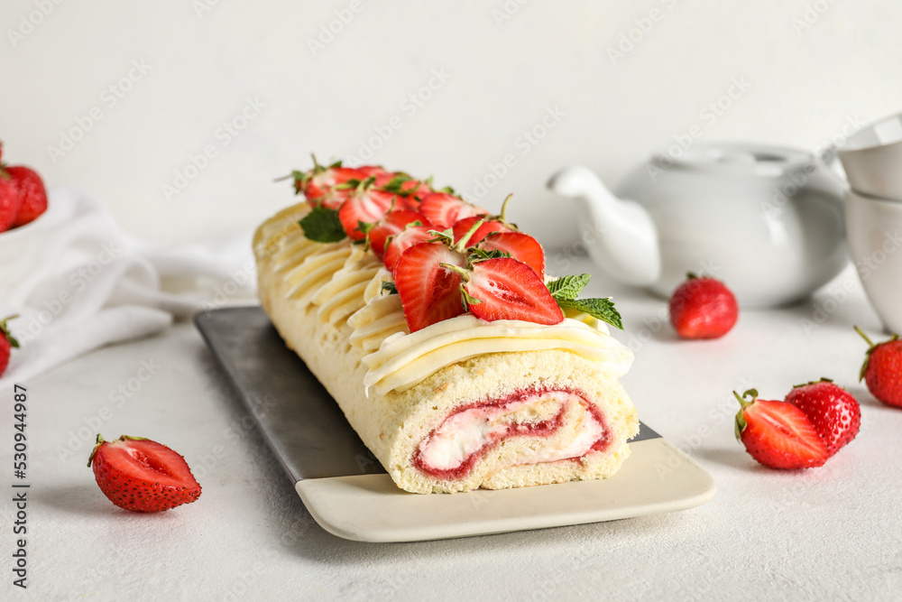 Plate with tasty strawberry roll cake on light background