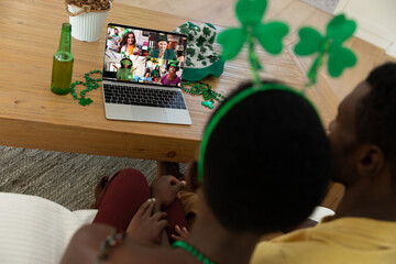 Sticker - African american couple making st patrick's day video call to friends on laptop at home