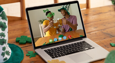 Poster - Webcam view of two african american men toasting beers on video call on laptop on wooden table