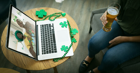 Sticker - Mixed race woman holding beer at bar making st patrick's day video call to friends on laptop screen