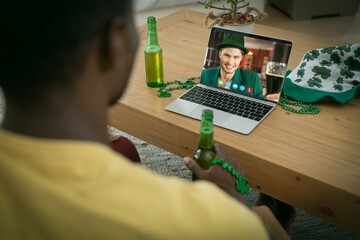 Poster - African american man holding a beer having a video call on laptop at home