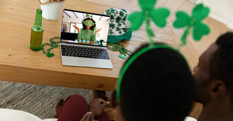 Sticker - African american couple making st patrick's day video call to friend in costume on laptop at home