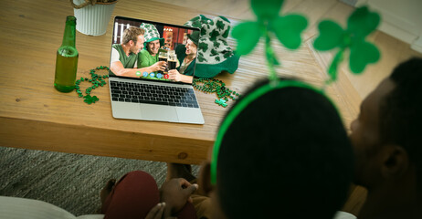 Poster - African american couple having st patrick's day video call with a group of friends on laptop at home