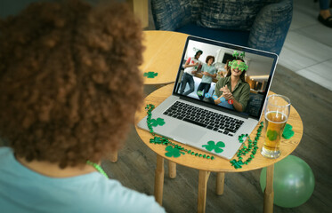 Wall Mural - Mixed race man at bar making st patrick's day video call to friends on laptop