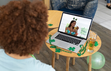 Poster - Mixed race man at bar making st patrick's day video call to female friend on laptop