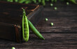 fresh pea pod open with peas on a wooden background