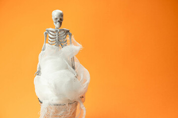 Wall Mural - skeleton in gauze on an orange background , Halloween concept