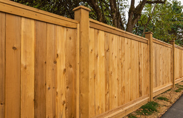 Nice new wooden fence around house. Wooden fence with green lawn. Street photo