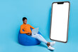 Full size photo of positive businessman surfing laptop sit next to placard poster promo isolated on blue color background