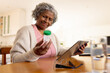 © Wavebreak Media - Happy senior african american women taking her medications and using tablet