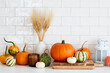 © photoguns - Still life harvest pumpkins, fall home decorations and vase of dry wheat on table in scandinavian kitchen interior.