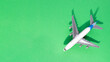 Leinwandbild Motiv Top view of white model plane, airplane toy on isolated green background. Flat lay with copy space. Trip or travel banner..