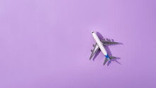 Top View Of White Model Plane, Airplane Toy On Isolated Purple Background. Flat Lay With Copy Space. Trip Or Travel Banner..