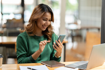 Wall Mural - Asian businesswoman in formal suit in office happy and cheerful during using smartphone and working.