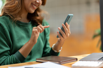 Wall Mural - Asian businesswoman in formal suit in office happy and cheerful during using smartphone and working.