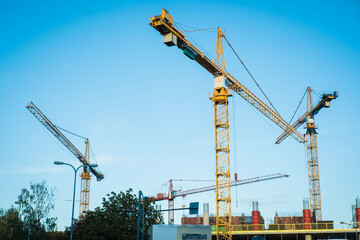 Many cranes working on a large construction site. Real estate development concept.