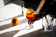 photography of a man's hand holding aperol spritz cocktail glass with orange slice 