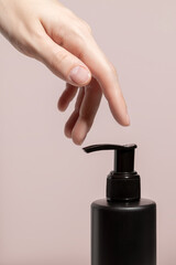 Wall Mural - A womans hand and black dispenser with a cream. Mockup.