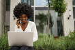 Young african american businesswoman working using laptop sitting on the bench in the city