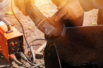 the hands of the master saw the metal with a grinder. metal works in the workshop close up