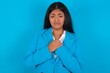 Sad Young latin woman wearing  blue blazer blue background desperate and depressed with tears on her eyes suffering pain and depression  in sadness facial expression and emotion concept