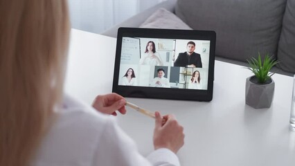 Wall Mural - Video conference. Elegant woman. Business teamwork. Blonde lady having online meeting on tablet computer with colleagues in light room interior.